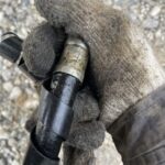 軍手で油圧ホースを持っている