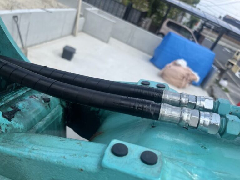 水色の重機に２本のホース